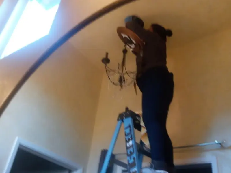 Electrician installing a chandelier in a West University Place residence